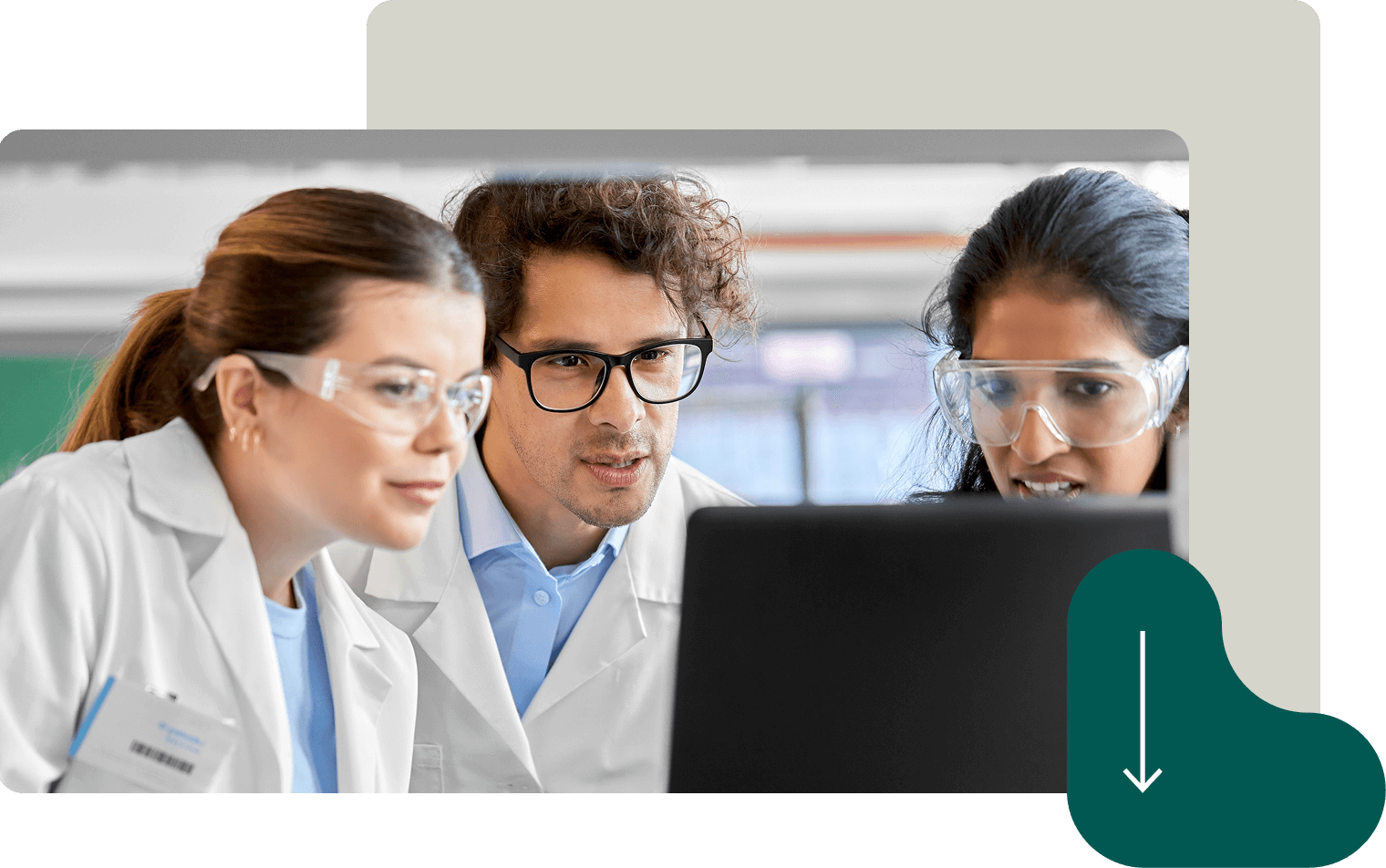 Three scientists in lab coats and safety glasses analyzing data on computer screen