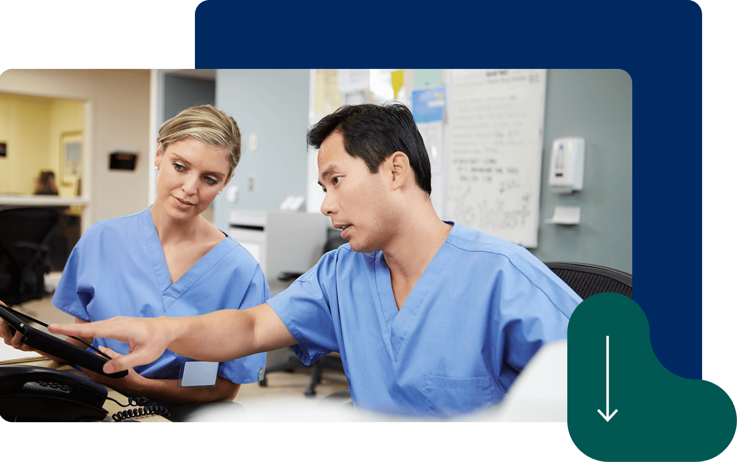 Two nurses in blue scrubs collaborating at computer workstation in medical facility